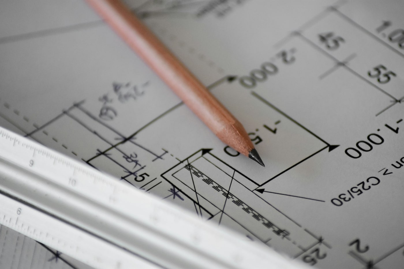 Illustrative photograph of a scale ruler and pencil over an architectural blueprint